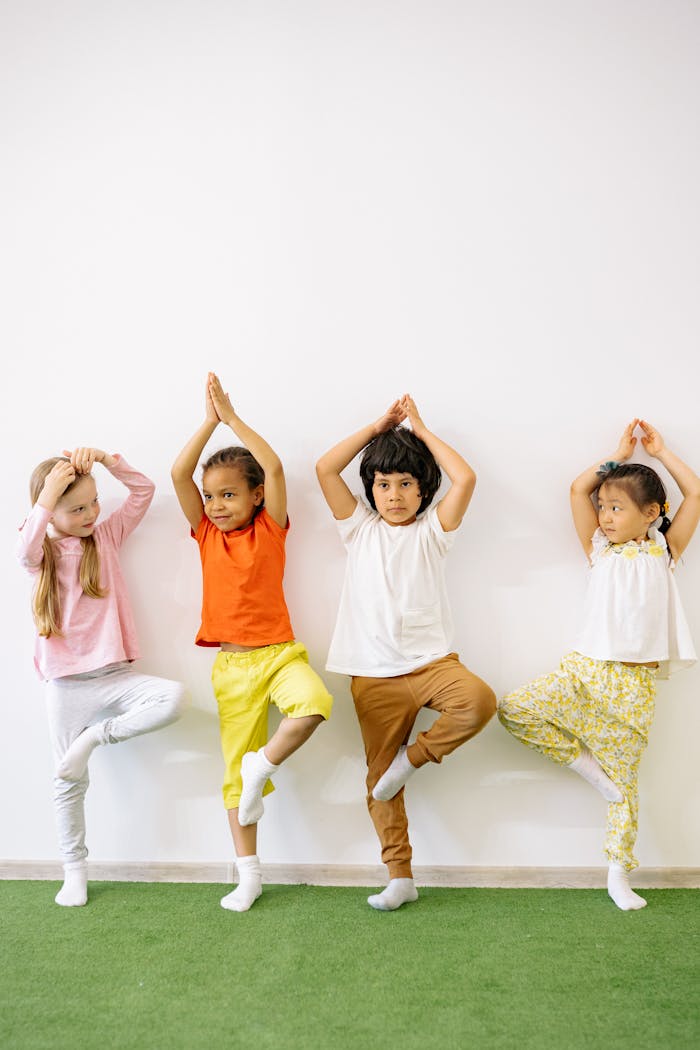 Home Four diverse children practicing yoga indoors, promoting fun and exercise in a learning environment.